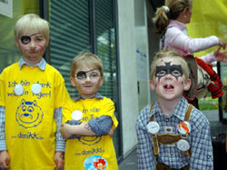  Zwei Kinder mit Piratenschminke und ein Kind mit geschminktem Batman-Symbol